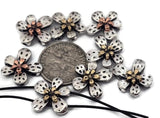These detailed silver 2‑hole slider beads showcase radiant five‑petal flowers with shimmering metallic centers. Crafted for balanced alignment in double‑strand projects, they’re perfect as bracelet focal beads or decorative spacers. The mix of silver, gold, and copper tones enhances both modern and rustic jewelry styles.