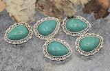 Western teardrop turquoise 2-hole sliders. These metal focal beads feature marbled turquoise cabochons and patterned silver edges. Two parallel holes stabilize leather lace, paracord, or beading wire so designs stay flat. Excellent bracelet beads, necklace beads, and hatband beads. Must-have jewelry findings and beads for beading in Southwestern and boho projects.