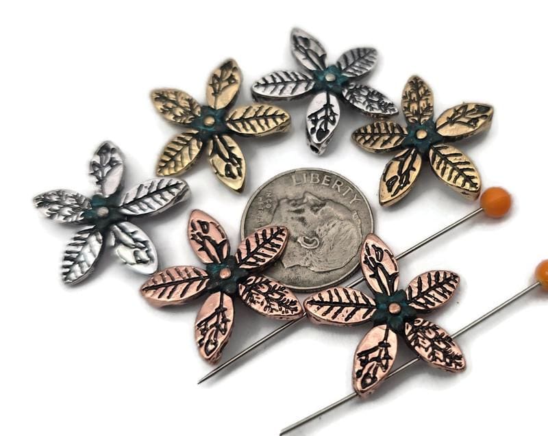 Floral two hole slider beads for jewelry making and crafting. Each five‑petal metal bead (silver, gold, copper) features leaf textures and a teal center, perfect as a flower focal, spacer, or connector. Build bracelet stacks with seed beads as filler beads, or use a single slider as a pendant connector and earring center. Pairs with gemstones, pearls, crystals, Czech glass, and other metallic beads. Essential beading components, findings, and supplies for DIY and small wholesale.