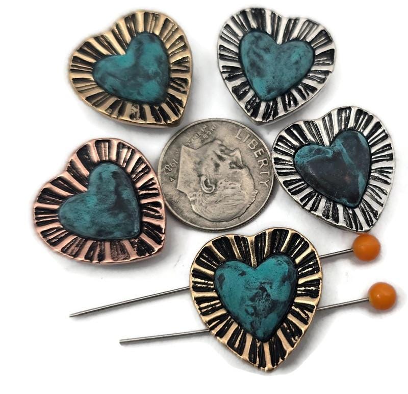 Mixed‑metal heart 2 hole slider beads with a turquoise patina center and sunburst border. Use these metal beads as focal sliders, spacers, or connector components in bracelet stacks, chokers, and necklaces. Frame with seed beads as filler beads; add crystals, pearls, or Czech glass for shimmer. The antique silver, gold, and copper finishes pair with earthy gemstones and other metallic beads. Essential beading components and findings for gifts, boho sets, and small‑batch wholesale.