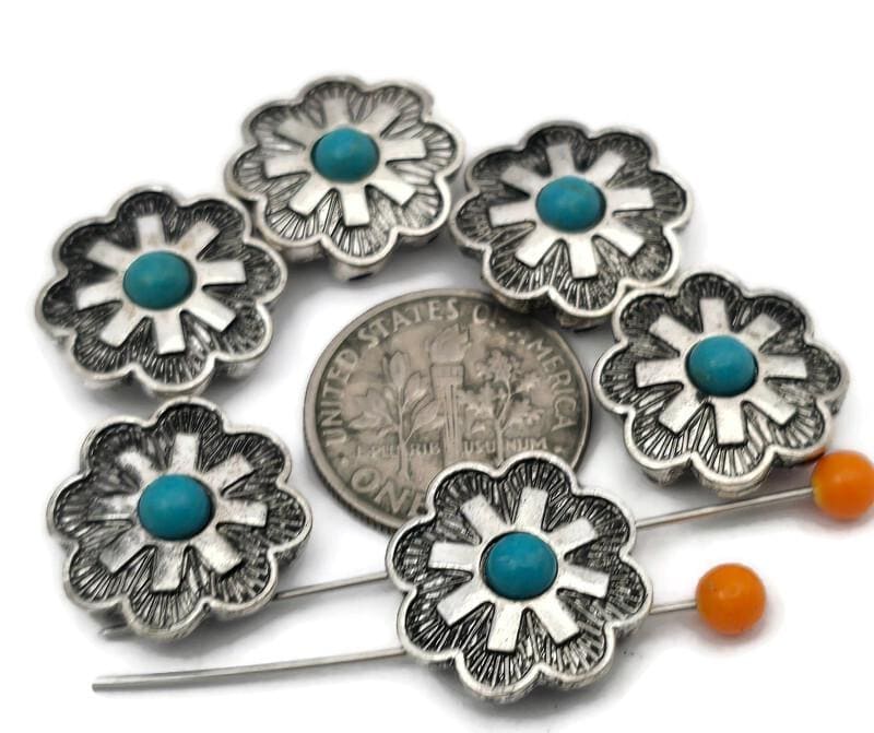 These Southwestern cross‑flower 2 hole slider beads feature a turquoise‑style center set in a bold silver‑tone floral design. The double‑hole construction keeps two strands aligned, making them ideal focal beads for leather bracelets, chokers, and hatbands. Pair with seed beads, Czech beads, heishi, or gemstone chips for classic Western jewelry. Beautiful bracelet beads and jewelry making components for boho, rodeo, and Southwestern beading projects.