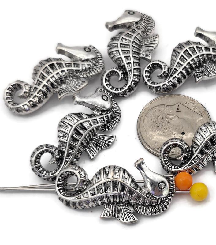 These detailed seahorse 2‑hole slider beads in platinum silver tone deliver dimensional ocean style. The dual channels act like spacer bars, keeping strands aligned in bracelets and necklaces. Pair these sea life beads with pearls, glass rounds, gemstone chips, coral‑look accents, and seed beads for coastal, tropical, and beach wedding designs. Durable metal beads with raised texture that adds depth to boho, nautical, and summer collections.
