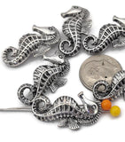 These detailed seahorse 2‑hole slider beads in platinum silver tone deliver dimensional ocean style. The dual channels act like spacer bars, keeping strands aligned in bracelets and necklaces. Pair these sea life beads with pearls, glass rounds, gemstone chips, coral‑look accents, and seed beads for coastal, tropical, and beach wedding designs. Durable metal beads with raised texture that adds depth to boho, nautical, and summer collections.