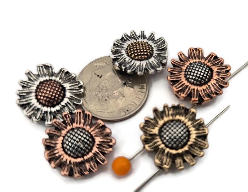 Brighten your jewelry designs with these sunflower 2‑hole slider beads in mixed metal finishes—antique silver, warm copper, and golden brass tones. Each daisy bead features dimensional petals and a textured seed center that adds depth and catches light beautifully. The dual holes act like a spacer bar, keeping double‑strand bracelets and necklaces aligned. Use as focal beads or slide beads between seed beads, pearls, gemstones, and crystals for boho, cottage, and garden‑inspired jewelry making.