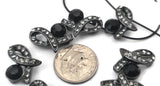 These edgy gunmetal ribbon slider beads are essential focal beads for modern jewelry making. Featuring a sculpted bow shape set with a bold jet black crystal and rows of sparkling black diamond rhinestones, they offer a sleek, dark sparkle. The 2‑hole connector design stabilizes double‑strand bracelets and prevents twisting. Mix with seed beads, silver spacers, or lava stones for boutique‑style jewelry making and unique DIY projects.