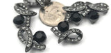 Create statement jewelry with these gunmetal 2‑hole focal slider beads. The ornate ribbon design is set with a large jet black rhinestone and shimmering black diamond crystals for a dramatic, monochromatic look. Use as bracelet connectors or centerpiece beads in multi‑strand necklaces to keep strands tidy and evenly spaced. Perfect with seed beads, hematite, and rhinestone spacers for DIY beading, crafting, and professional jewelry supplies.