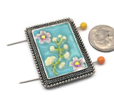 Elevate your jewelry making with this stunning aqua enamel floral focal bead. Set in a decorative antique silver frame, this 2-hole slider bead features hand-painted style flowers with sparkling rhinestone centers. Ideal as a centerpiece for multi-strand bracelets or statement necklaces, it keeps strands perfectly spaced. This unique metal bead is a must-have for beading, crafting, and designers looking for high-quality, vintage-inspired jewelry findings.