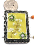 Brighten your jewelry collection with this unique focal 2-hole slider bead, featuring a cheerful yellow enamel background and a delicate floral design. Framed in textured antique silver metal, this large rectangular bead is perfect for creating high-end bracelets and necklaces. The two-hole construction ensures your jewelry stays flat and aligned. Pair with seed beads, pearls, or gemstone beads for a professional, artisan look in your handmade jewelry projects.