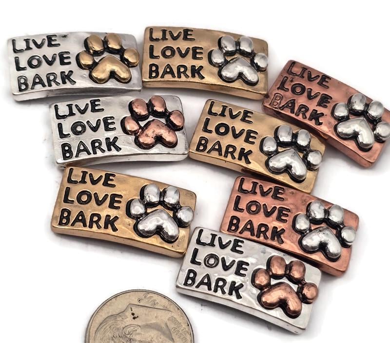These 2 hole slider beads feature a sweet Live Love Bark paw print design in mixed metals with antique detailing in silver, gold, and copper tones. Perfect metal slide spacer components for two strand double bracelets or necklaces, these beads sit beautifully between seed beads, duo beads, or other spacer metal beading supplies. Ideal for dog lover jewelry, pet themed bracelets, or DIY beading projects, these unique jewelry making components and findings add personality to your designs.