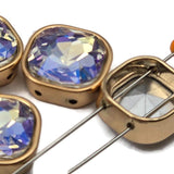 Clear aurora borealis square double hole slider beads in warm gold bezel setting. These color-shifting 2 hole spacer beads are perfect for festival jewelry, layered bracelets, and multi-strand necklaces. Unique rhinestone findings compatible with CzechMates, tile beads, and carrier beads. A favorite among beaders and jewelry designers.