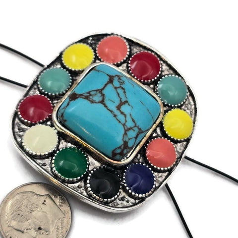 Make a bold statement in your jewelry designs with this large 43 mm western style focal slider bead. Featuring a turquoise style center stone surrounded by vibrant enamel accents, this oversized bead creates a striking centerpiece for handmade jewelry. Designed with two holes for double strand bracelets or necklaces, it pairs beautifully with leather cord, seed beads, gemstone beads, and spacer beads. Perfect for western jewelry, cowgirl accessories, and southwestern statement designs.