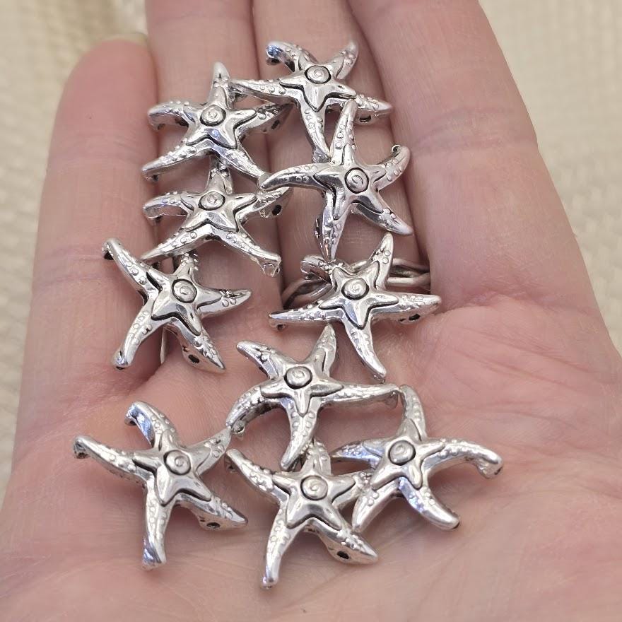 Antique silver starfish 2 hole slider beads, 21mm x 21mm, 8.5mm between holes, qty 10. Rare hard to find coastal focal beads with detailed textured finish perfect for beach inspired jewelry, boho necklaces, and nautical bracelet designs. Pair with turquoise, freshwater pearls, coral, seed beads, and hematite as supporting components. Perfect anchor point for peyote stitch and loom work. Unique metal findings for beaders and jewelry designers.