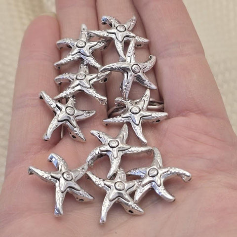 Antique silver starfish 2 hole slider beads, 21mm x 21mm, 8.5mm between holes, qty 10. Rare hard to find coastal focal beads with detailed textured finish perfect for beach inspired jewelry, boho necklaces, and nautical bracelet designs. Pair with turquoise, freshwater pearls, coral, seed beads, and hematite as supporting components. Perfect anchor point for peyote stitch and loom work. Unique metal findings for beaders and jewelry designers.