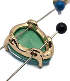 Six faceted teardrop rhinestone slider beads in a Seafoam Green AB finish shown on a white background. Their polished gold settings complement the sparkling blend of aqua blue, turquoise, lime, and seafoam green reflections. A dime and beading needles provide scale while showcasing the bead size. These 2 Hole Slider Beads are excellent focal components for bracelets, necklaces, earrings, keychains, and bead woven jewelry projects.
