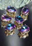 Gold pear-shaped 2 hole slider bead with a sparkling Purple Aqua AB rhinestone. The faceted stone displays amethyst purple tones accented by bright aqua and teal flashes. Ideal focal component for custom bracelets, necklaces, earrings, and jewelry making supplies.