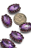 Elegant marquise-shaped focal beads featuring lavender violet center stones surrounded by shimmering amethyst rhinestones. The silver-tone settings add contrast and enhance the sparkle of the faceted stones. A dime provides size reference while a beading pin demonstrates the dual-hole design. These 2 Hole Slider Beads are excellent for multi-strand bracelets, statement necklaces, handmade pendants, custom earrings, and artistic jewelry making projects.