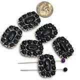 Western focal bead with a polished black center stone framed by coordinating black oval stones and antique silver detailing throughout the setting. The rectangular shape creates a bold centerpiece for jewelry designs. Shown with a dime for scale and pins demonstrating the stringing holes, these slider beads work beautifully in bracelets, necklaces, leather jewelry, artisan accessories, and handcrafted western designs.