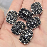 Decorative western-style focal beads featuring glossy black stones and antique silver detailing. The rectangular shape and dual-hole construction make them ideal centerpiece components for multi-strand jewelry designs. A dime demonstrates the bead size while beading pins show the stringing configuration. Perfect for handmade bracelets, statement necklaces, leather jewelry, custom beadwork, and western-inspired accessories.