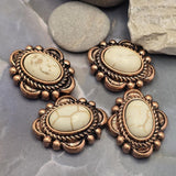 Rustic western-inspired 2 Hole Slider Beads featuring cream faux marble stones framed by detailed antique copper settings. The neutral stone color and warm metal finish create a versatile jewelry component suitable for many design styles. Displayed with beading pins to show stringing orientation, these focal beads are excellent for bracelets, necklaces, artisan beadwork, leather jewelry, and handmade accessories.