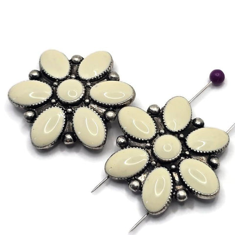 Flower-shaped 2 Hole Slider Beads featuring soft cream enamel petals arranged around a matching enamel center and set in antique silver metal. Displayed beside a dime for size reference, these floral focal beads offer a decorative centerpiece for handmade bracelets, necklaces, earrings, pendants, bead weaving projects, and feminine jewelry designs with vintage-inspired charm.