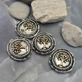 Mixed metal Tree of Life slider beads with detailed raised tree designs framed by decorative beaded borders. The antique silver backgrounds contrast beautifully with the antique copper and light antique gold tree accents. Shown on a hand for scale, these focal beads work beautifully in Bracelet Making, Necklace Designs, custom jewelry, and artisan handcrafted accessories.