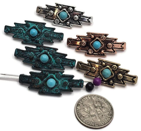 Southwestern-style 2 Hole Slider Beads featuring faux turquoise center stones set in mixed finishes including antique silver, antique copper, antique brass, and verdigris patina. The geometric focal beads display bold tribal-inspired patterns with decorative floral accents and raised metal details. A dime and beading pins are included for size reference. Perfect for handmade bracelets, western necklaces, artisan jewelry, leather projects, and Southwestern-inspired jewelry making designs.