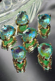 Close-up of six pear-shaped Seafoam AB rhinestone slider beads arranged beside a dime and beading needles for scale. The faceted rhinestones display shimmering seafoam green, turquoise, aqua blue, and yellow-green flashes created by the Aurora Borealis finish. Each bead is set in a polished gold setting and features two parallel holes, making them perfect focal beads for handmade jewelry and multi-strand bracelet designs.