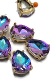 Decorative pear-shaped Purple Aqua AB rhinestone slider bead in a polished gold setting. The faceted rhinestone combines rich purple tones with bright aqua and turquoise reflections. Designed with two stringing holes for multi-strand jewelry projects, these beads are perfect for bracelets, necklaces, bead weaving, and custom jewelry making supplies.