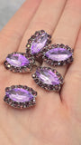 Five faceted violet focal beads with sparkling amethyst rhinestone accents displayed on a clean white background. The marquise shape creates an elegant profile, while the silver-tone setting complements the purple color palette. A dime offers size comparison and a beading pin shows the dual-hole construction. These slider beads are perfect for multi-strand jewelry, handmade necklaces, bracelets, bead weaving, and artisan jewelry projects.