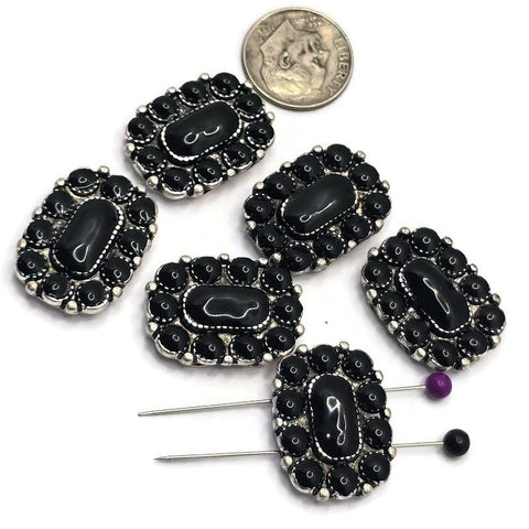 Large rectangular western-style 2 Hole Slider Beads featuring a glossy black center stone surrounded by matching black oval stones in an antique silver setting. Displayed with a dime for size reference and beading pins showing the dual-hole construction, these focal beads are perfect for handmade bracelets, western necklaces, leather jewelry, custom accessories, and Southwestern-inspired jewelry making projects.