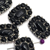 Western-inspired rectangular focal bead with glossy black stones and textured antique silver accents. The dual-hole design helps maintain strand alignment in multi-strand jewelry creations. Photographed with a dime for scale, these slider beads are excellent for handmade bracelets, layered necklaces, leather projects, custom jewelry collections, and rustic Southwestern-style accessories that require a bold centerpiece.