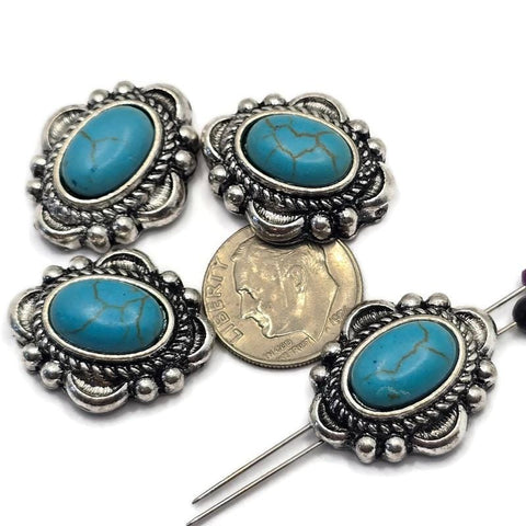 Western-style 2 Hole Slider Beads featuring oval faux turquoise stones with natural-looking matrix veining set in detailed antique silver settings. Displayed with a dime for size reference and beading pins showing the dual-hole construction, these focal beads are perfect for handmade bracelets, western necklaces, leather jewelry, Southwestern accessories, and artisan jewelry making projects.