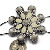 Decorative western-style slider bead showcasing cream and white enamel details framed by textured antique silver metalwork. The large circular shape and intricate design make it ideal as a jewelry centerpiece. Displayed beside a dime for size reference, this dual-hole focal bead works beautifully in bracelets, necklaces, leather projects, and handcrafted statement jewelry.