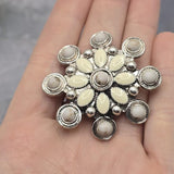 Western-inspired statement bead featuring soft cream enamel accents arranged around a central decorative element. The antique silver setting includes raised bead details and textured metalwork that enhance the overall design. Displayed with a dime for size comparison, this large 2 Hole Slider Bead is ideal for bracelets, necklaces, bead weaving, leather jewelry, and artisan handcrafted accessories.