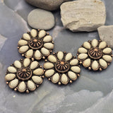 Western floral slider beads with cream faux stone accents set in richly detailed antique copper metalwork. The flower-inspired design creates an eye-catching centerpiece suitable for many jewelry styles. A dime provides size comparison while beading pins demonstrate the dual-hole construction. Ideal for bracelet making, necklace designs, leather jewelry, handcrafted accessories, and rustic western-inspired jewelry collections.