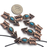 Arrow-shaped 2 Hole Slider Beads featuring faux turquoise center stones set in antique copper metal. Displayed with a dime for size reference, these western-inspired focal beads showcase decorative arrowhead details and feathered tails. Perfect for handmade bracelets, necklaces, leather jewelry, Southwestern accessories, artisan jewelry projects, and custom western-themed jewelry making designs.