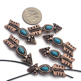 Antique copper 2 Hole Slider Beads shaped like arrows and accented with oval faux turquoise stones. The western-inspired design combines warm copper tones with vibrant turquoise color for a classic Southwestern appearance. Shown with a dime for scale, these focal beads are ideal for bracelet making, necklace designs, beadwork projects, and artisan-crafted jewelry.