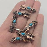 Western-style arrow slider beads with bright faux turquoise center stones and antique copper detailing. The decorative arrow design includes geometric accents and textured metalwork that create rustic Southwestern appeal. Displayed with a dime and stringing material for reference, these dual-hole beads work beautifully in bracelets, necklaces, leather accessories, and handcrafted jewelry collections.