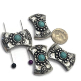 Antique silver 2 Hole Slider Beads featuring turquoise-look center stones with natural-looking veining. The curved shape and decorative western styling make them excellent focal beads for jewelry projects. Shown on a hand for size reference, these beads are suitable for handmade bracelets, necklaces, beadwork, leather jewelry, and artisan-crafted Southwestern accessories.