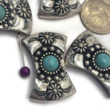 Southwestern-inspired focal beads featuring bright faux turquoise stones and antique silver detailing. The curved design sits beautifully in bracelet projects while the decorative silver accents create texture and dimension. Displayed on a gray background with decorative stones, these 2 Hole Slider Beads are ideal for handmade jewelry and western-inspired accessories.