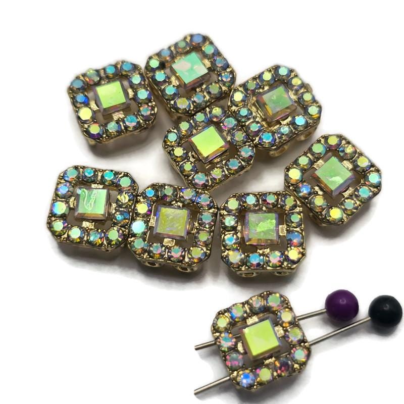 Add dazzling sparkle to your jewelry designs with these Clear AB Rhinestone 2 Hole Slider Beads. Featuring a bright gold finish and shimmering Aurora Borealis rhinestones, these focal beads display flashes of pink, blue, green, gold, and lavender as they catch the light. Perfect for bracelet making, necklace designs, earrings, pendants, and multi-strand jewelry, their dual-hole construction also makes them ideal for bead weaving, Peyote Stitch, and loom work projects.