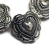 Create heartfelt handmade jewelry with these antique silver Heart Concho Slider Beads. The raised heart center symbolizes love, family, and friendship, while the surrounding decorative metalwork adds texture and visual interest. Perfect for bracelet making, necklace designs, artisan jewelry, leather jewelry, and custom accessories, these focal beads feature dual holes for stability and easy integration into multi-strand jewelry and bead weaving projects.