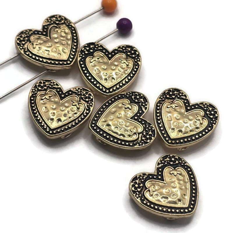 These bright gold 2 Hole Slider Beads with antique detailing feature a beautifully textured heart centerpiece surrounded by decorative floral accents and a beaded border. Perfect as focal beads for bracelet making, necklace designs, earrings, and pendants, their dual-hole construction keeps multi-strand jewelry aligned while adding warmth and vintage-inspired charm. A wonderful addition to jewelry making supplies for romantic, Western, and artisan handmade jewelry.