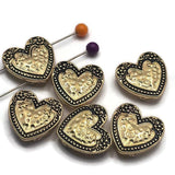 These decorative Heart Slider Beads feature a polished bright gold finish accented with antique detailing that highlights the floral border and textured heart center. Their two-hole design makes them excellent focal beads for bracelet making, necklace designs, pendants, and artisan jewelry. Pair them with gemstones, pearls, crystals, leather, or seed beads to create timeless handmade jewelry with warmth and character.