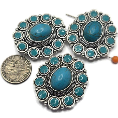 Create beautiful Western-inspired jewelry with these Silver Turquoise 2 Hole Slider Beads. Featuring a large faux turquoise center stone surrounded by smaller turquoise accents in an ornate silver concho setting, these focal beads are perfect for bracelets, necklaces, and multi-strand jewelry. Pair them with leather, natural stone beads, or silver findings to create rustic, Southwestern, rodeo, and boho jewelry with timeless Western charm.