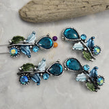 Bring garden-inspired beauty to your jewelry designs with these Blue Floral 2 Hole Slider Beads. Featuring hand-painted enamel leaves, sparkling blue crystals, and an antique silver finish, these metal focal beads are perfect for bracelets, necklaces, earrings, and mixed-media jewelry. Pair them with pearls, Czech glass, gemstones, or leather to create unique floral jewelry with professional-looking results.