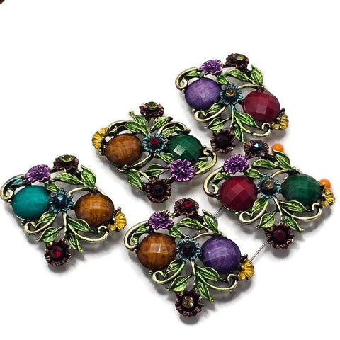 These Floral 2 Hole Slider Beads feature an antique gold finish with colorful faceted stones, detailed enamel flowers, and leafy vines for an elegant botanical design. These decorative metal focal beads are perfect for bracelets, necklaces, and multi-strand jewelry. Pair them with gemstones, pearls, seed beads, or leather to create nature-inspired handmade jewelry filled with color, texture, and timeless floral charm.