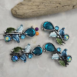 Add vibrant color to your handmade jewelry with these Blue Floral 2 Hole Slider Beads. Designed as decorative metal focal beads, they feature faceted blue crystals, shimmering rhinestones, and detailed enamel leaves that create a graceful botanical look. Perfect for bracelet making, necklace designs, and artisan jewelry, these two-hole beads provide excellent strand alignment and endless creative possibilities.