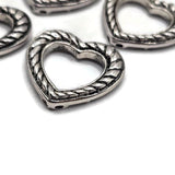Antique silver heart focal bead with an open center and textured braided rope design. This 2 hole slider bead features hidden back loops for creative stringing, double strand bracelets, seed bead embellishment, bead weaving, necklaces, and handmade jewelry making.