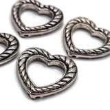 Open heart 2 hole slider bead in antique silver with dimensional twisted rope texture and dark recessed detailing. Silver jewelry component for handmade bracelets, double strand jewelry, bead weaving, seed bead projects, necklaces, and romantic heart jewelry designs.